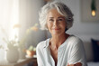 © Darya - Smiling middle aged mature grey haired woman looking at camera, happy old lady posing at home indoor, positive single senior retired female sitting on sofa in living room headshot portrait