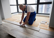 © anatoliy_gleb - Man in work overalls using metal construction ruler and pen while drawing line on laminate flooring board. Male floor installer preparing laminate plank for installation in apartment under renovation.