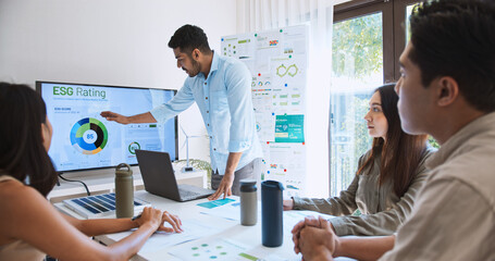 Wall Mural - Asian Indian man lead young group of multiethnic businesspeople in team meeting, using laptop computer for ESG topic presentation on monitor. Sustainable business practice, people work at home concept