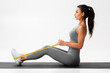 © nikolas_jkd - Athletic girl doing resistance band exercise for back on gray background. Fitness woman working out