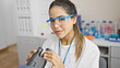 © Krakenimages.com - Hispanic woman scientist using microscope in laboratory setting, embodying expertise and healthcare professionalism.