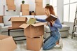 © Krakenimages.com - Young caucasian woman smiling confident putting books on cardboard box at new home