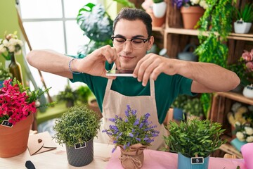 Sticker - Young hispanic man florist make photo to lavender plant by smartphone at flower shop