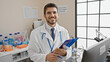 © Krakenimages.com - Young hispanic man in lab coat with clipboard and stethoscope standing in a laboratory.