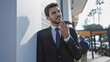 © Krakenimages.com - Handsome hispanic man in suit using smartphone on sunny urban street
