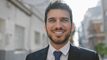 Wall Mural - Portrait of a smiling hispanic man with a beard in a suit on a sunny urban street.