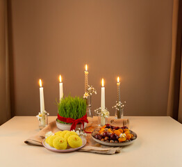 Wall Mural - Beautiful Novruz setting on peachy neutral background with fresh semeni wheat glass with red ribbon, candles and traditional Azerbaijani pastry  on the table, dried fruits and eggs and daffodils