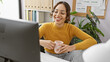 © Krakenimages.com - Smiling woman with glasses drinking coffee at her modern office desk, emanating professionalism and comfort.