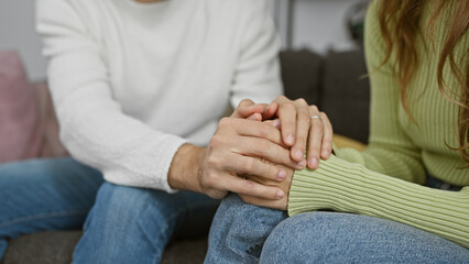 Poster - A couple sitting closely on a couch at home, holding hands to show affection and emotional support between a man and a woman.