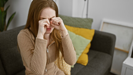 Sticker - A stressed young woman rubbing her eyes at home, showing signs of fatigue or headache.