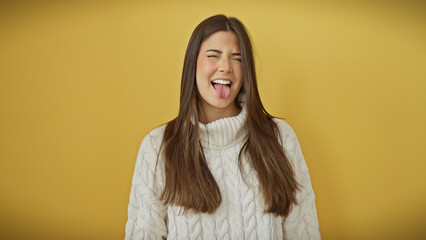 Sticker - A playful young woman sticks out her tongue, wearing a sweater against a vibrant yellow background.