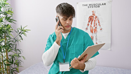 Canvas Print - Handsome young hispanic man, a committed rehab therapist, dives into reading medical document while expertly balancing a smartphone conversation at busy rehab clinic