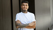 © Krakenimages.com - Portrait of a young, confident latin man, sporting a tattoo, cheerfully standing on a city street while expressing joy. his smiling face exudes positivity, his arms crossed in a gesture of confidence.