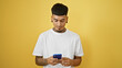 © Krakenimages.com - Cool tattooed young latin man concentrates on texting, his serious expression illuminated by isolated yellow background