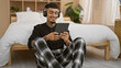 © Krakenimages.com - Young latin man using touchpad sitting on the floor wearing headphones at bedroom