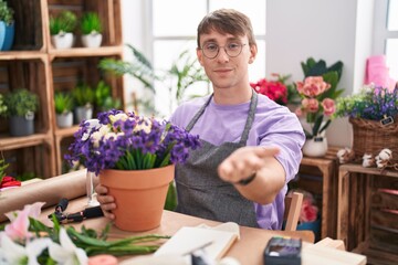 Poster - Caucasian blond man working at florist shop smiling cheerful offering palm hand giving assistance and acceptance.