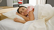 © Krakenimages.com - A young hispanic woman peacefully sleeping in a bedroom, showcasing relaxation and comfort at home.