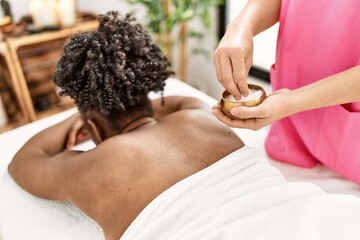 Poster - African american woman lying on massage table having facial treatment at beauty salon