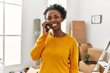 Canvas Print - African american woman talking on smartphone standing at new home