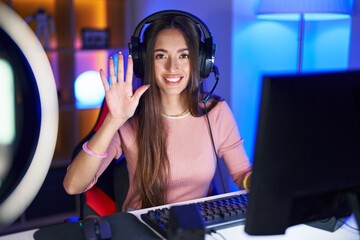 Sticker - Young hispanic woman playing video games showing and pointing up with fingers number five while smiling confident and happy.