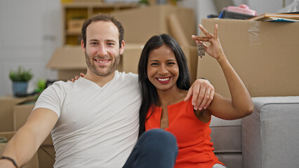 Wall Mural - Beautiful couple sitting on floor together holding keys at new home