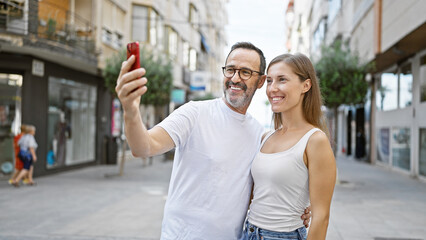 Poster - Confident father and daughter share a lovely moment, joyfully taking a cool selfie on their mobile phone standing on a bustling city street.