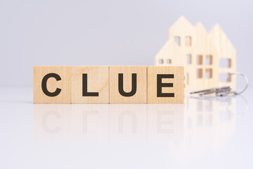 Poster - wooden cubes on a table with text CLUE, model house and keys on background. concept of business, financial, investment, economy. gray background