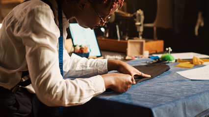 Wall Mural - Tailor measuring fabric in workshop, checking material measurements, custom made clothing line. Employee working on luxury fashion collection in fashion atelier. Handheld shot. Close up.