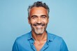 © Asier - Portrait of a handsome middle aged man smiling at camera while standing against blue background