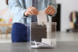 © Pixel-Shot - Voting young woman near ballot box at polling station, closeup
