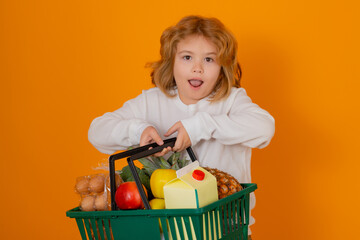 Wall Mural - Child with grocery basket, isolated studio portrait. Concept of shopping at supermarket. Shopping with grocery cart. Grocery store, shopping basket. Banner for grocery food store or supermarket.