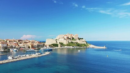 Poster - The city of Calvi and its medieval fort at the foot of the green mountains, in Europe, France, Corsica, by the Mediterranean Sea, in summer, on a sunny day.