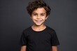 Portrait of a happy little boy in black t-shirt against grey background