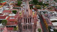 Towering Pink Spire Of Parroquia De San Miguel Arcangel In San Miguel De Allende, Guanajuato, Mexico. Aerial Pullback, Tilt-down