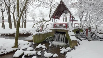 Wall Mural - Old water mill in Topilche park in Ternopil city, Ukraine, Europe. Stunning winter scene of the shore of Strypa river. Snowy morning view of city park. 4K video (Ultra High Definition)..