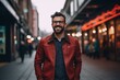 Portrait of a handsome young man wearing glasses and a red jacket in the city.