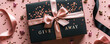 Elegant black gift box with GIVEAWAY in golden letters and confetti, tied with a satin ribbon on a pink background, perfect for contests and promotions