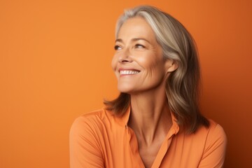 Portrait of smiling senior woman looking up over orange background with copy space