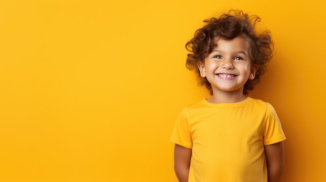 a cute little boy, smiling, stands on a yellow background. a happy child, the concept of joy, surpri