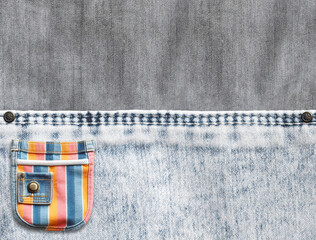 Wall Mural - Grey and light grey denim background with a seam and colourful pocket. Light gray color denim jeans fabric texture and striped multicolor pouch. Copy space for text