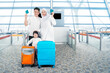 Happy muslim family of three holding passports posing with suitcases