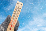 Fototapeta  - White celsius scale thermometer in hand. Ambient temperature minus 20 degrees celsius