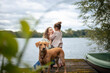 © Westend61 - Happy woman having fun with daughter near dog in front of lake