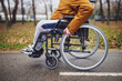 Close up image of paraplegic handicapped man in wheelchair in park. He is rolling on pathway.