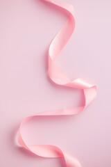 Wall Mural - Curled pink ribbon on pink background.