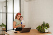 © Westend61 - Woman carrying baby girl and doing online shopping on laptop at home