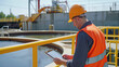 Environmental engineer in a reflective vest inspecting a wastewater treatment plant with a digital tablet.