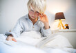© Westend61 - Boy reading book in bedroom at home