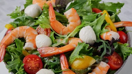 Poster - Vegetarian fresh salad with shrimps mozzarella cheese tomatoes arugula peppers rotating on plate. Close up