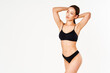 © GVS - Smiling sporty woman in black underwear posing on white studio background